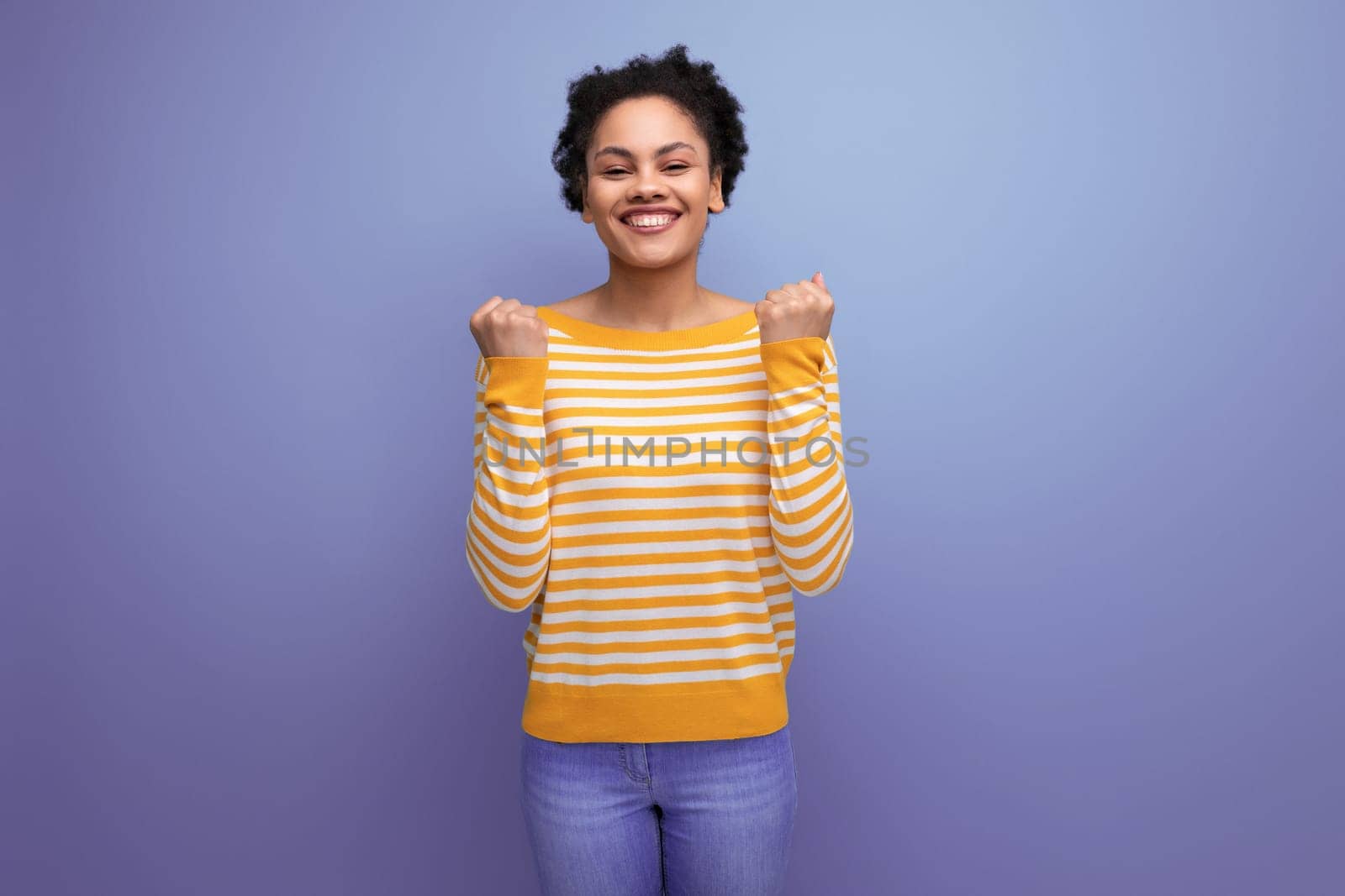 smiling brunette brown-haired young woman in a yellow striped sweater by TRMK