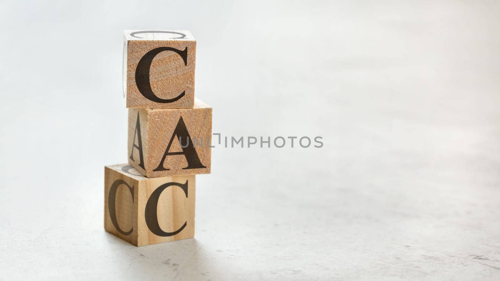 Pile with three wooden cubes - letters CAC meaning Customer Acquisition Cost on them, space for more text / images at right side.