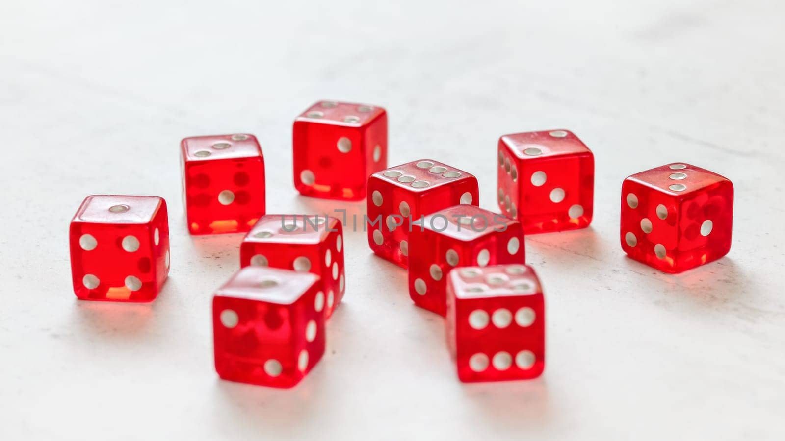Ten red translucent craps dices on white board showing different numbers.