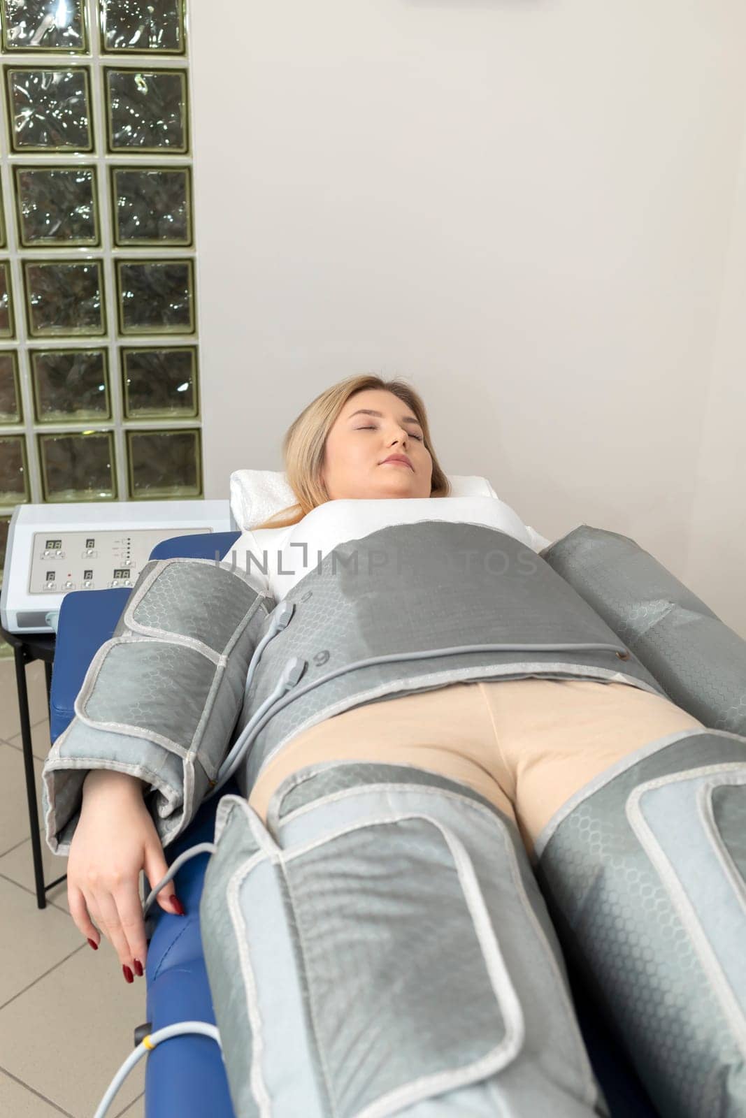 Pressure therapy procedure. Woman lying in massaging suit in spa clinic, treatment of varicose veins, edema, lymphatic drainage, weight loss. Relaxation,cure. Pressotherapy machine. Vertical