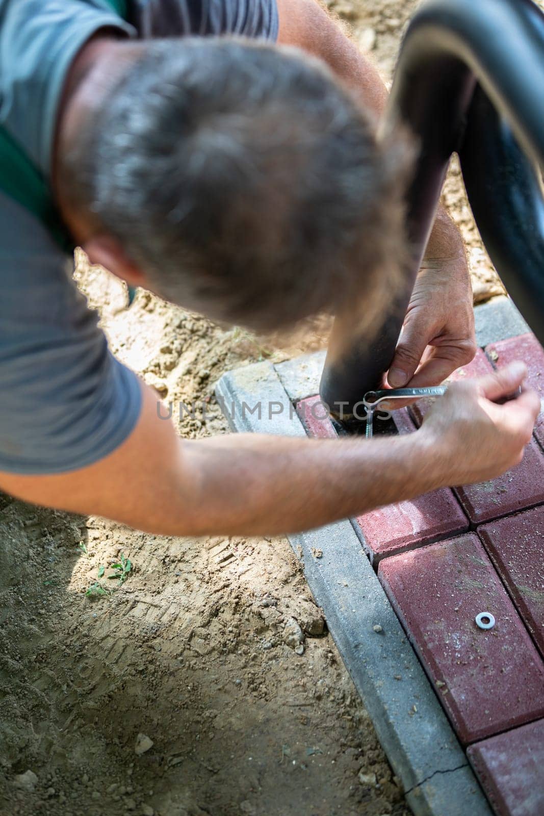 A worker during the installation of a new bench in a city park. New bowls for sitting and relaxing outdoors.