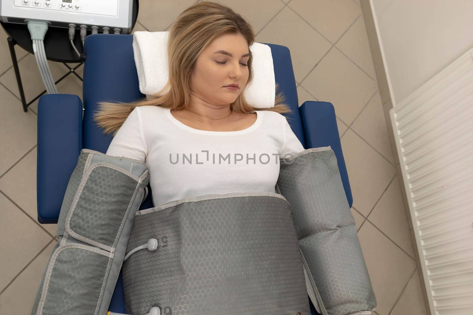 Top view pressure therapy procedure. Woman lying in massaging suit in hospital, treatment of varicose veins, edema, lymphatic drainage, weight loss. Relaxation,cure. Pressotherapy concept. Horizontal