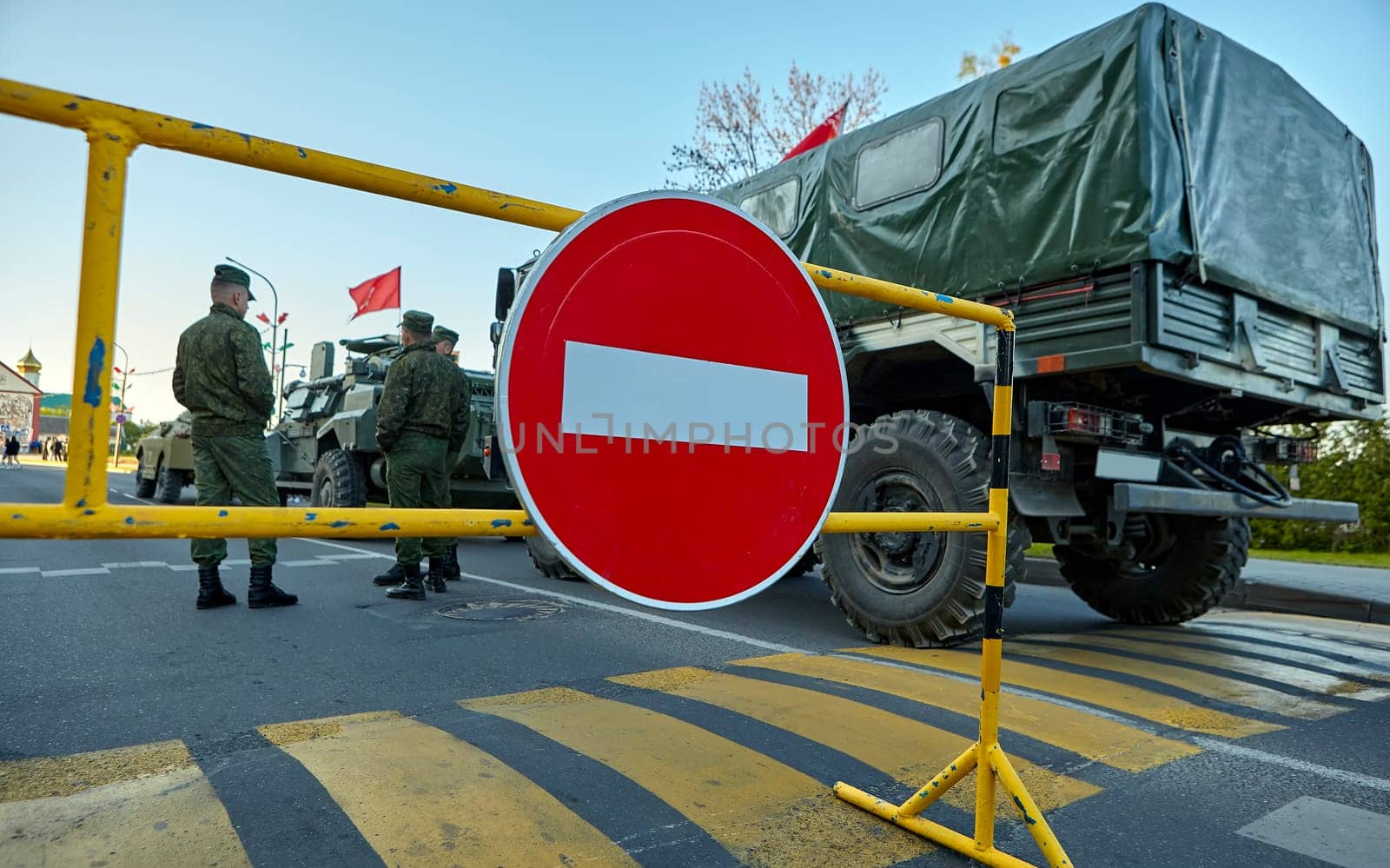 Soldiers stand near the car against the background of the STOP sign. The Belarusian military is conducting exercises.