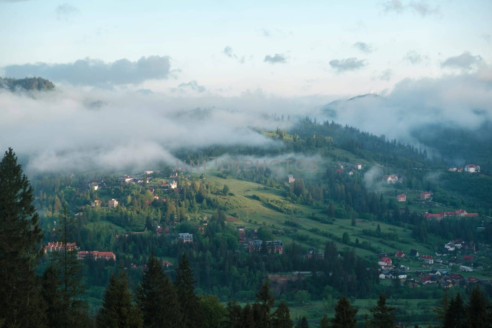 mountainous rural landscape at sunset. beautiful scenery with forests, hills and meadows in evening light. ridge with high peak in the distance. village in the distant valley by igor010