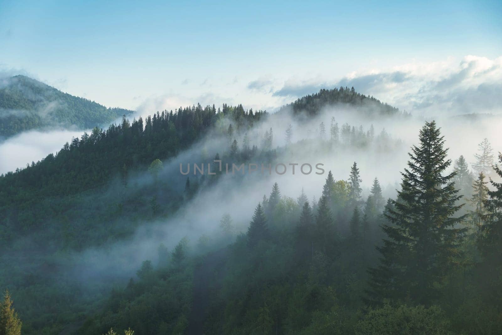 Mountain range with visible silhouettes through the morning colorful fog. download photo