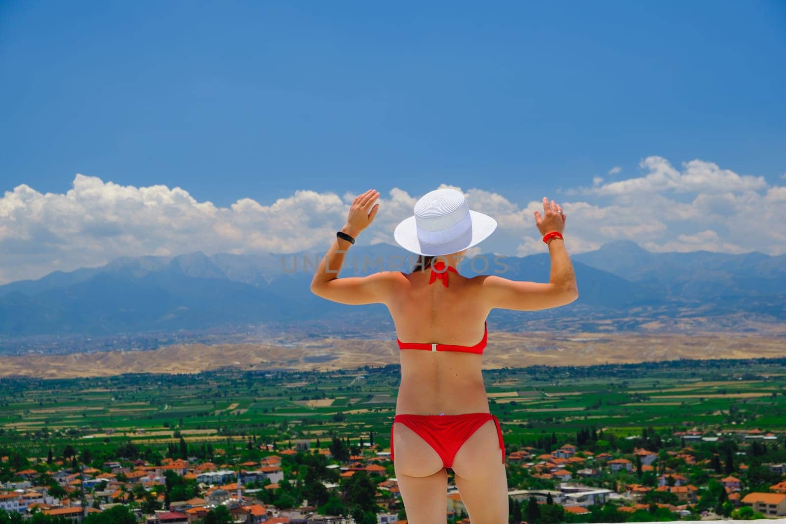 Happy woman enjoying vocation, joyful in summer beautiful view. Beautiful bikini model happy on travel wearing beach sun hat in Turkey by igor010