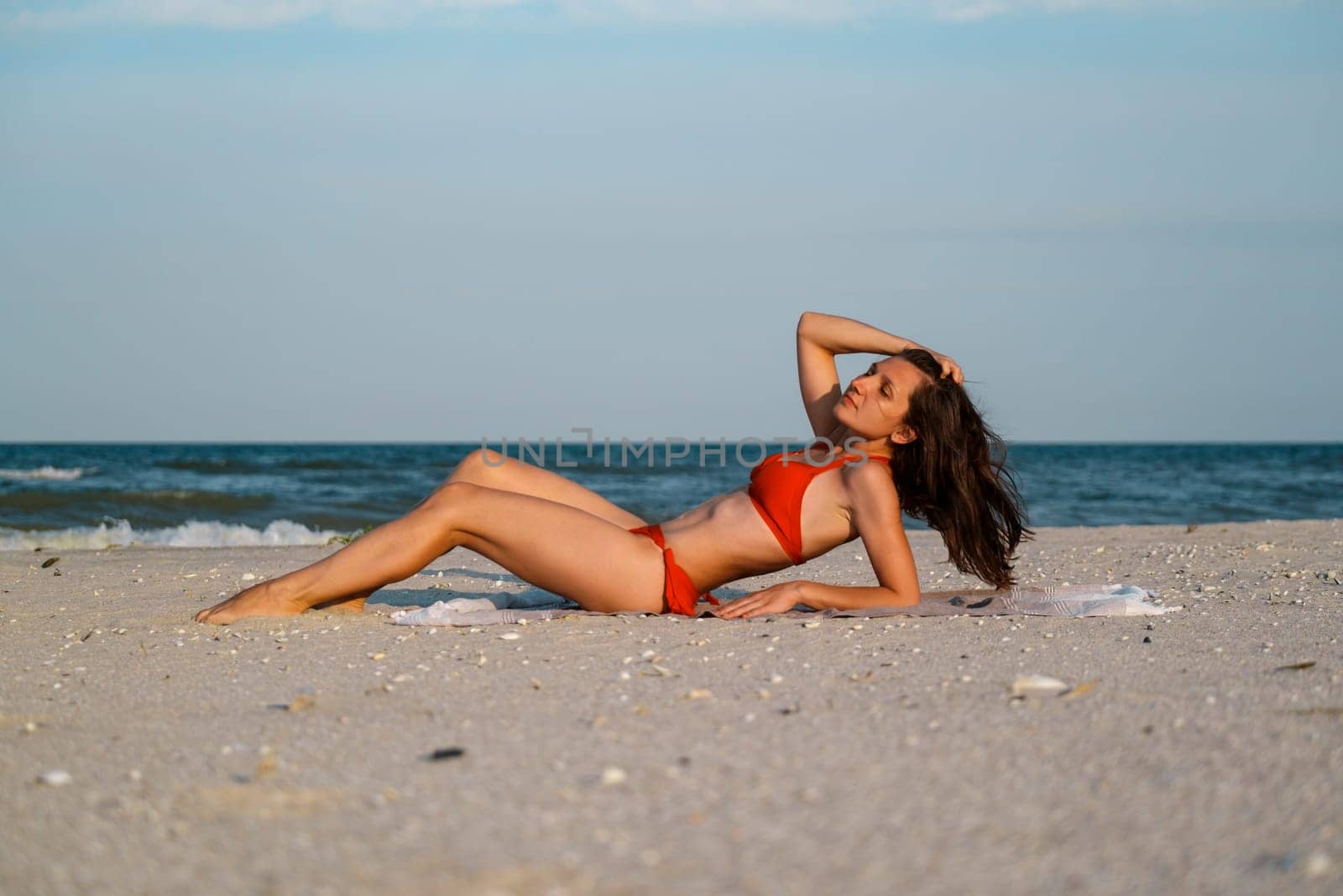 Latin stylish woman relaxing at tropical beach during summer vacation. Portrait of carefree tanned girl relaxing at sea with copy space. Young woman enjoying breeze, looking away, touching hairs by igor010