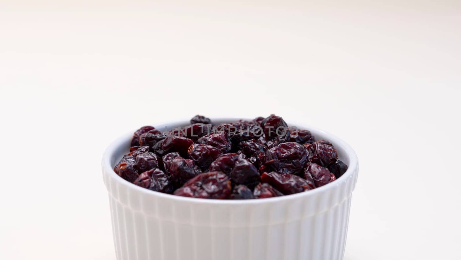 Closeup Superfood Heap Of Dried Cranberries In White Bowl On Beige Background. Selective Focus. Sweet Dehydrated Cranberries. Nutrients And Vitamins. Horizontal Plane. High quality photo