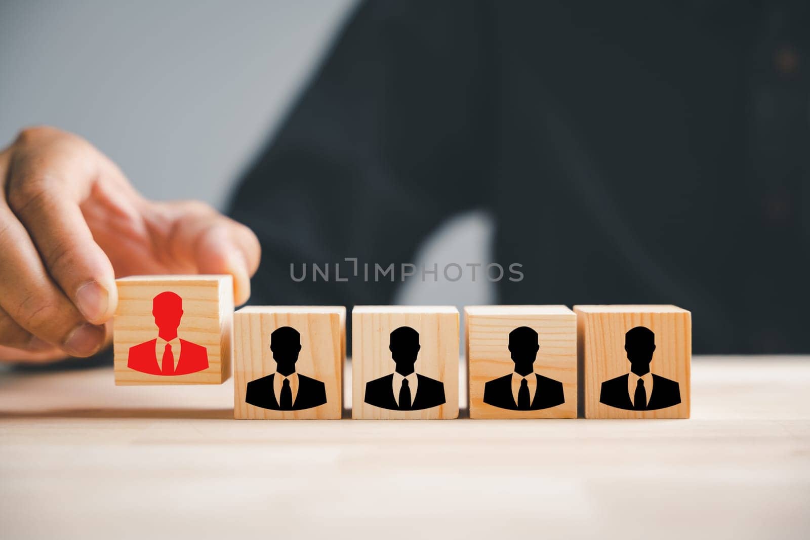 Hand picking up red human icon on wooden block. Business hiring recruitment. Career opportunity. HR Management. Leadership empowering new leaders. Shaping future workforce. Human resource management