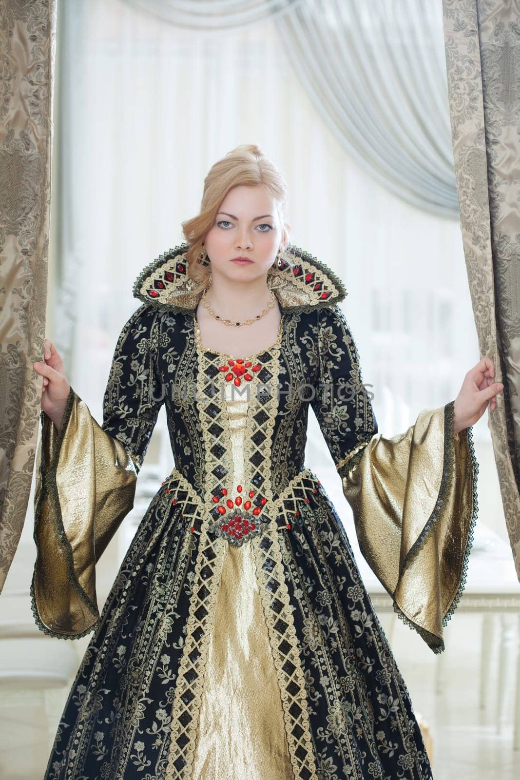 Image of unsmiling young woman posing in luxurious royal dress