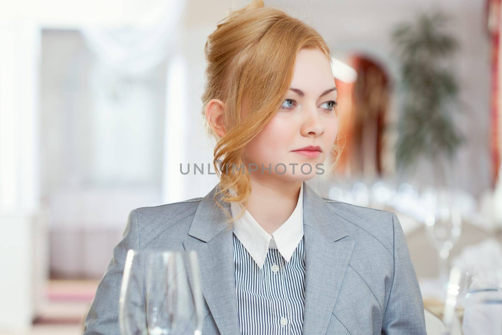 Confident young woman posing at table in restaurant, close-up