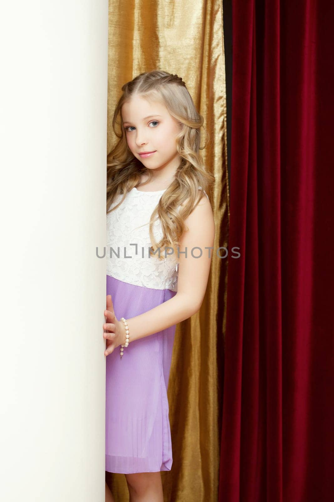 Cute curly girl posing on curtain backdrop, close-up