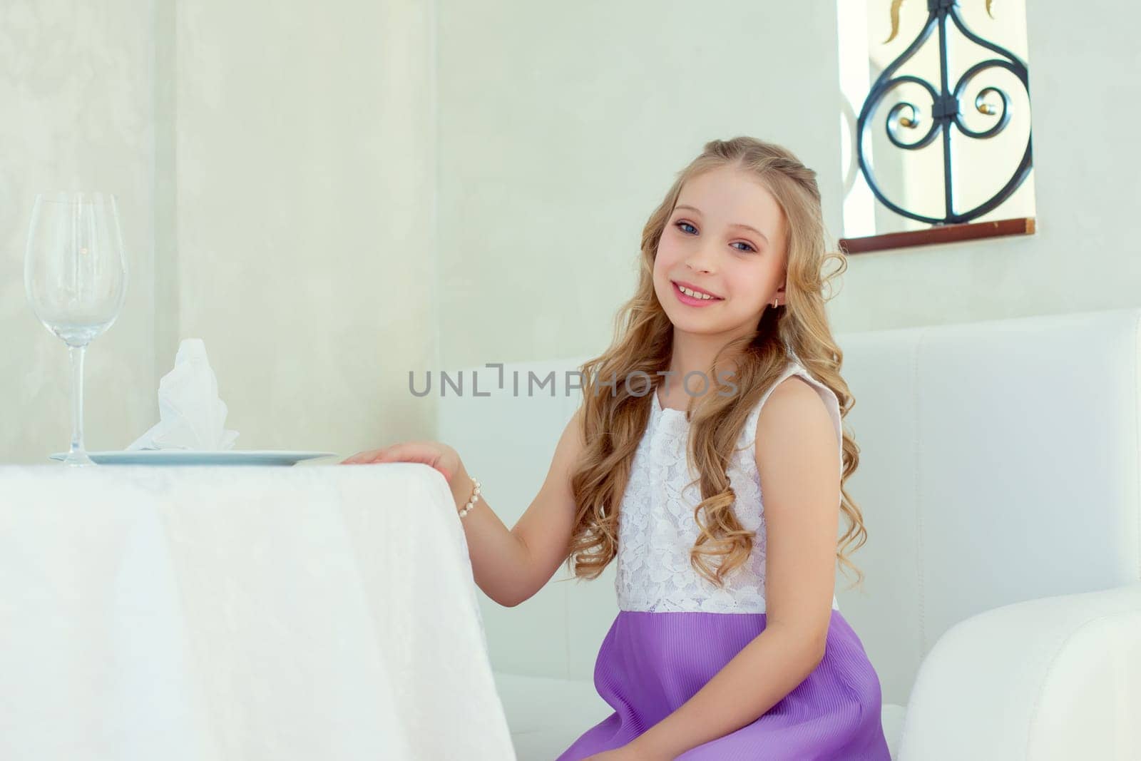 Image of adorable smiling girl posing at table, close-up