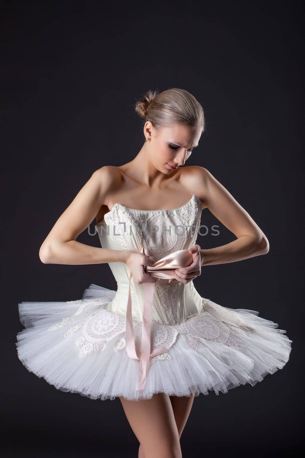 Concentrated pretty ballet dancer kneads pointe in studio