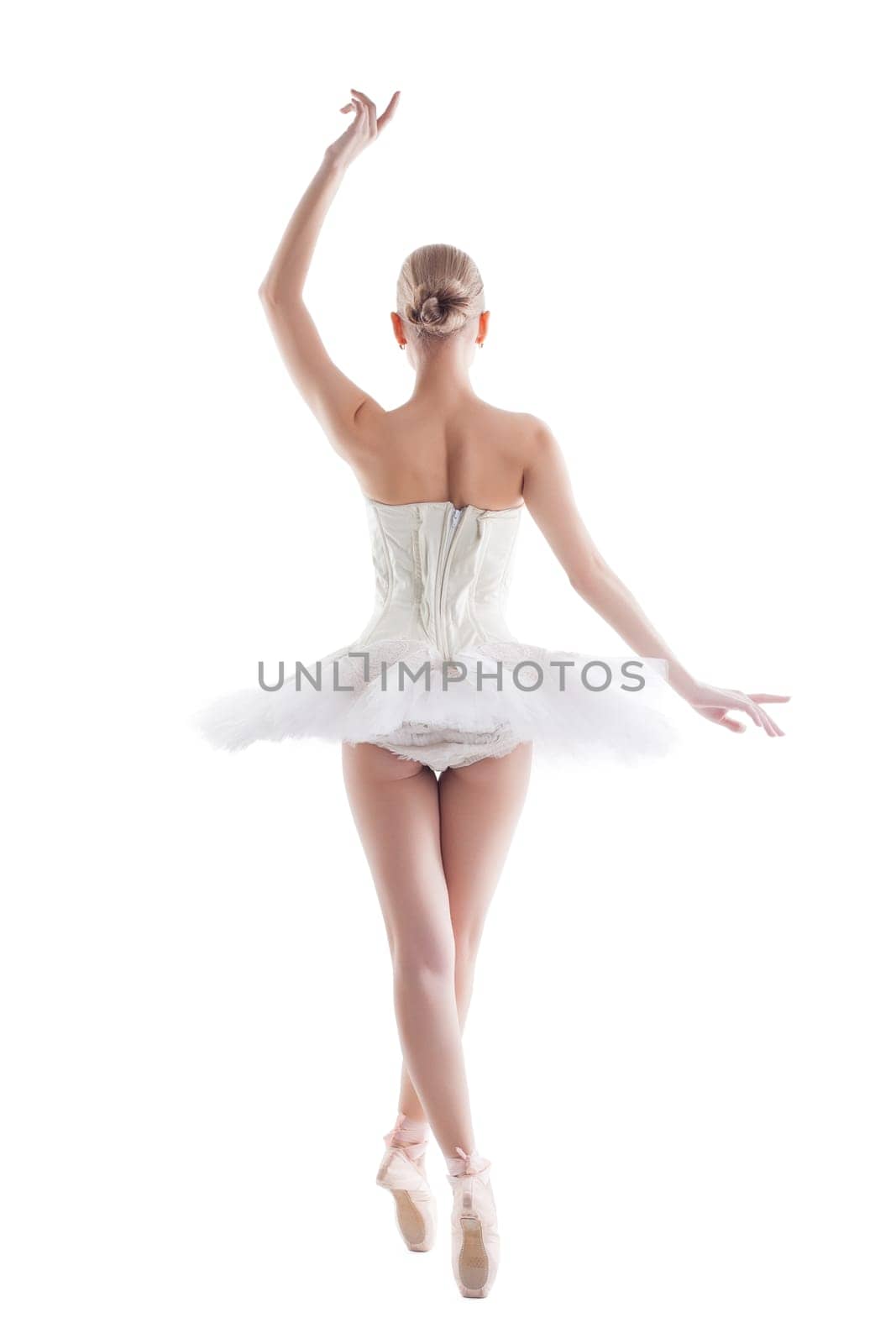 Rear view of slender young ballerina posing in tutu, isolated on white