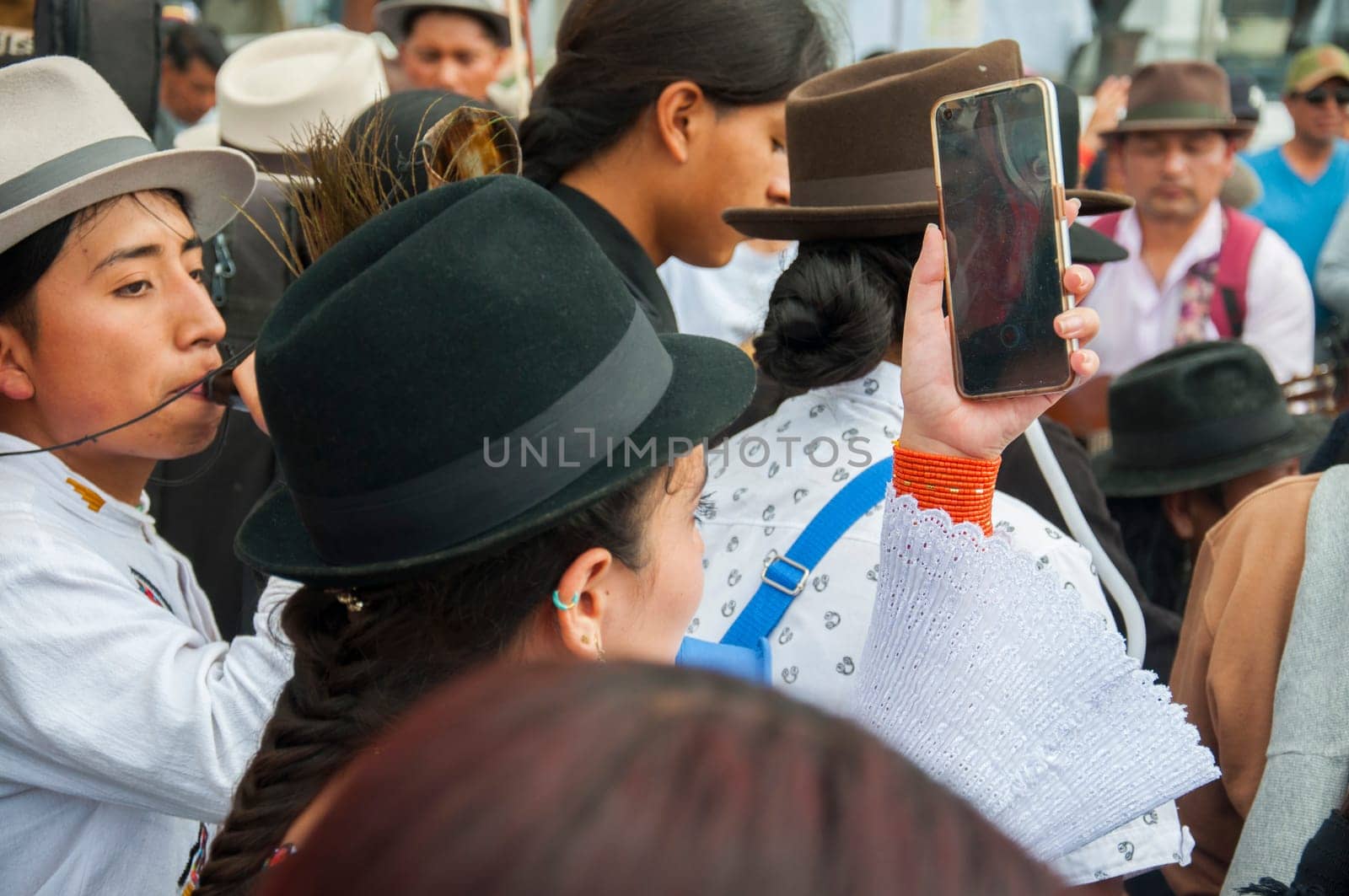 Otavalo, Ecuador - 24 de junio de 2023: indigenous woman recording with a cell phone the festival of inti raymi in otavalo ecuador. High quality photo