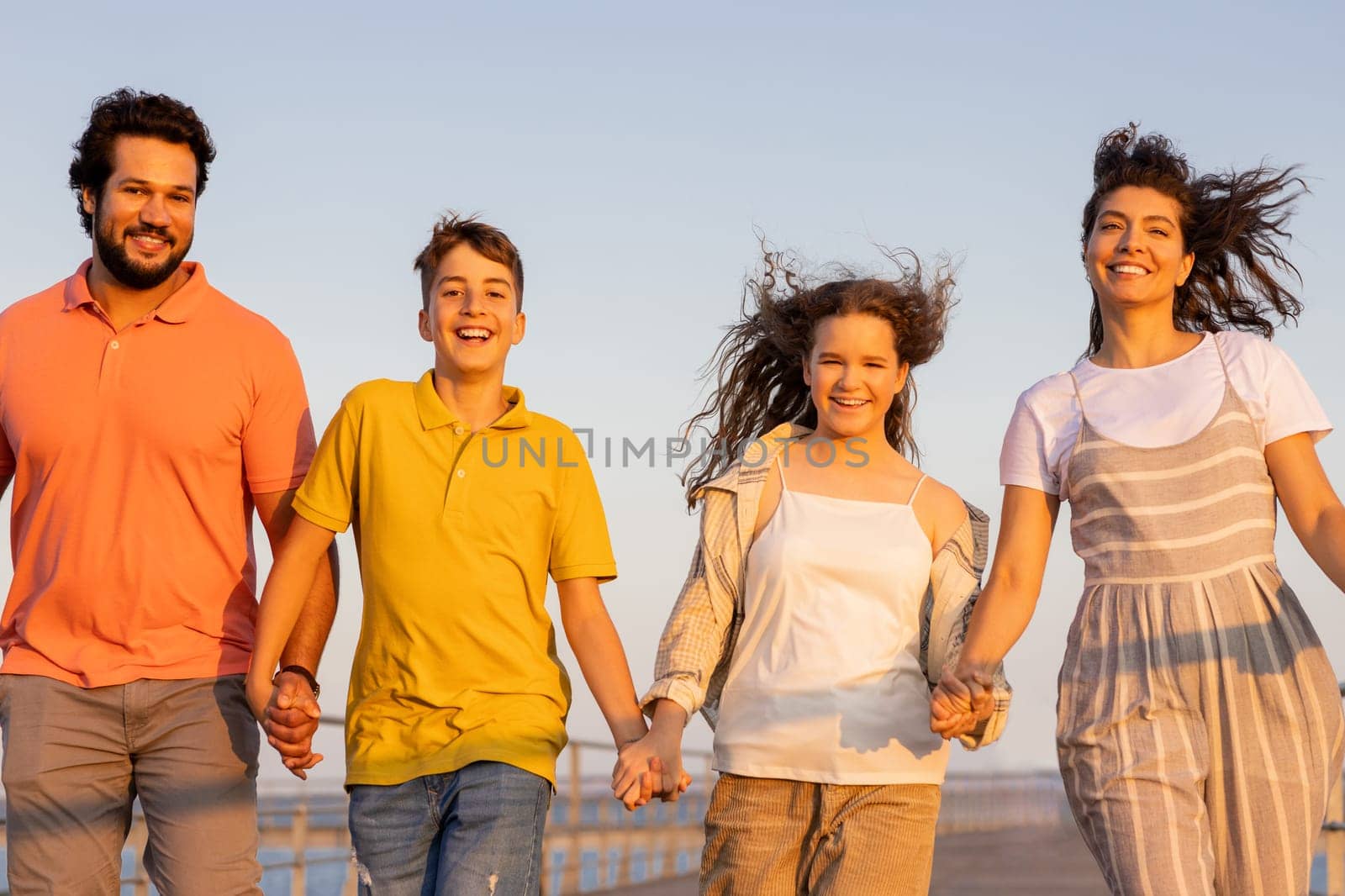 Smiling european millennial parents and teen kids holding hands, enjoy vacation, active lifestyle and walk. Free time at summer, weekends with family outdoor, childhood and parenting