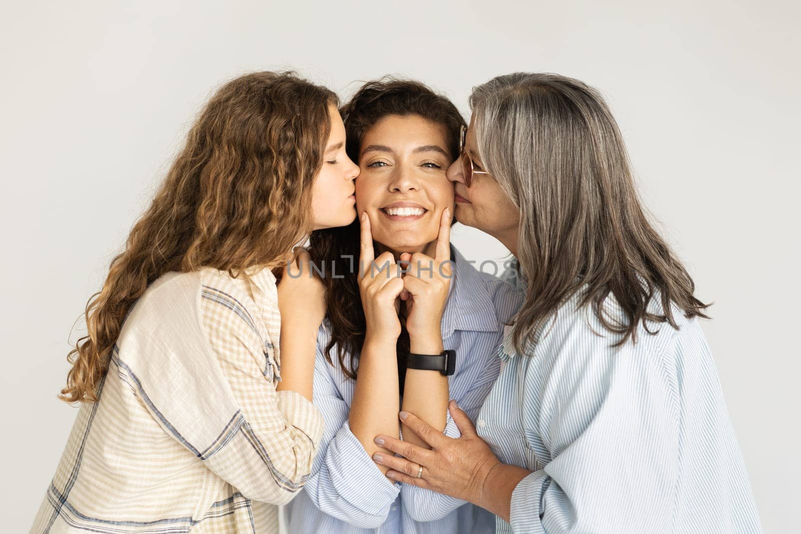 Glad caucasian old woman and teen girl kissing on cheeks adult lady, isolated on white studio background. Family support, love, female generation, mother-daughter relationship, beauty care