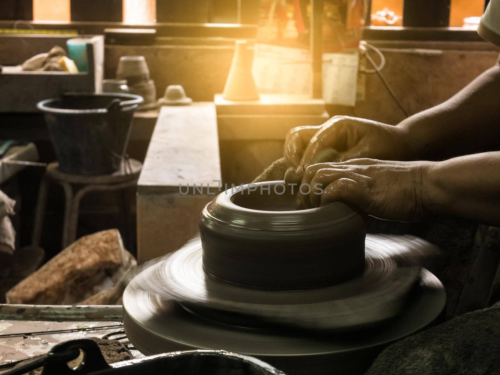 potter's hands shaping soft clay to make an earthen pot by Wmpix
