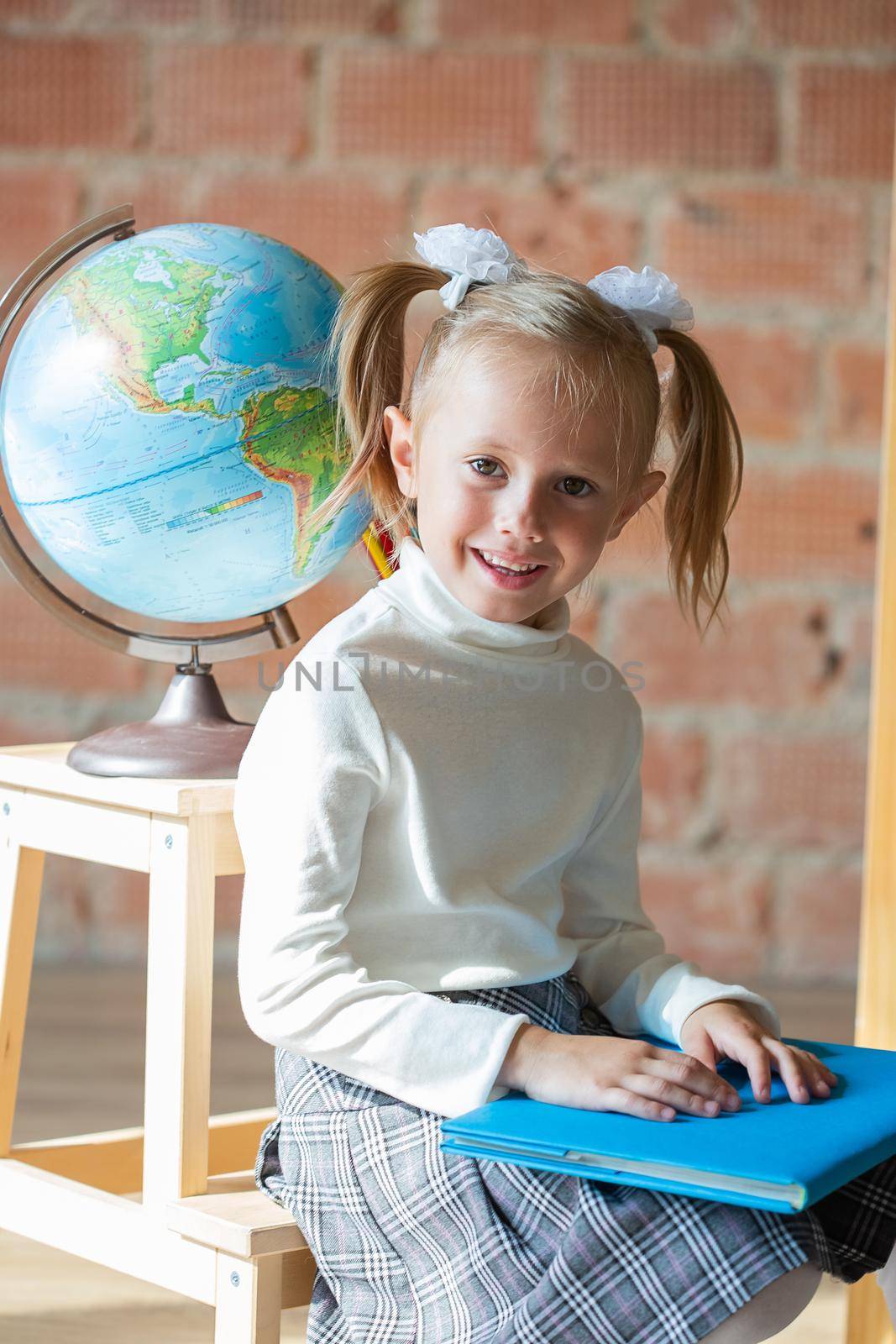 Close-up portrait of caucasian schoolgirl sitting in front of the globe in the classroom