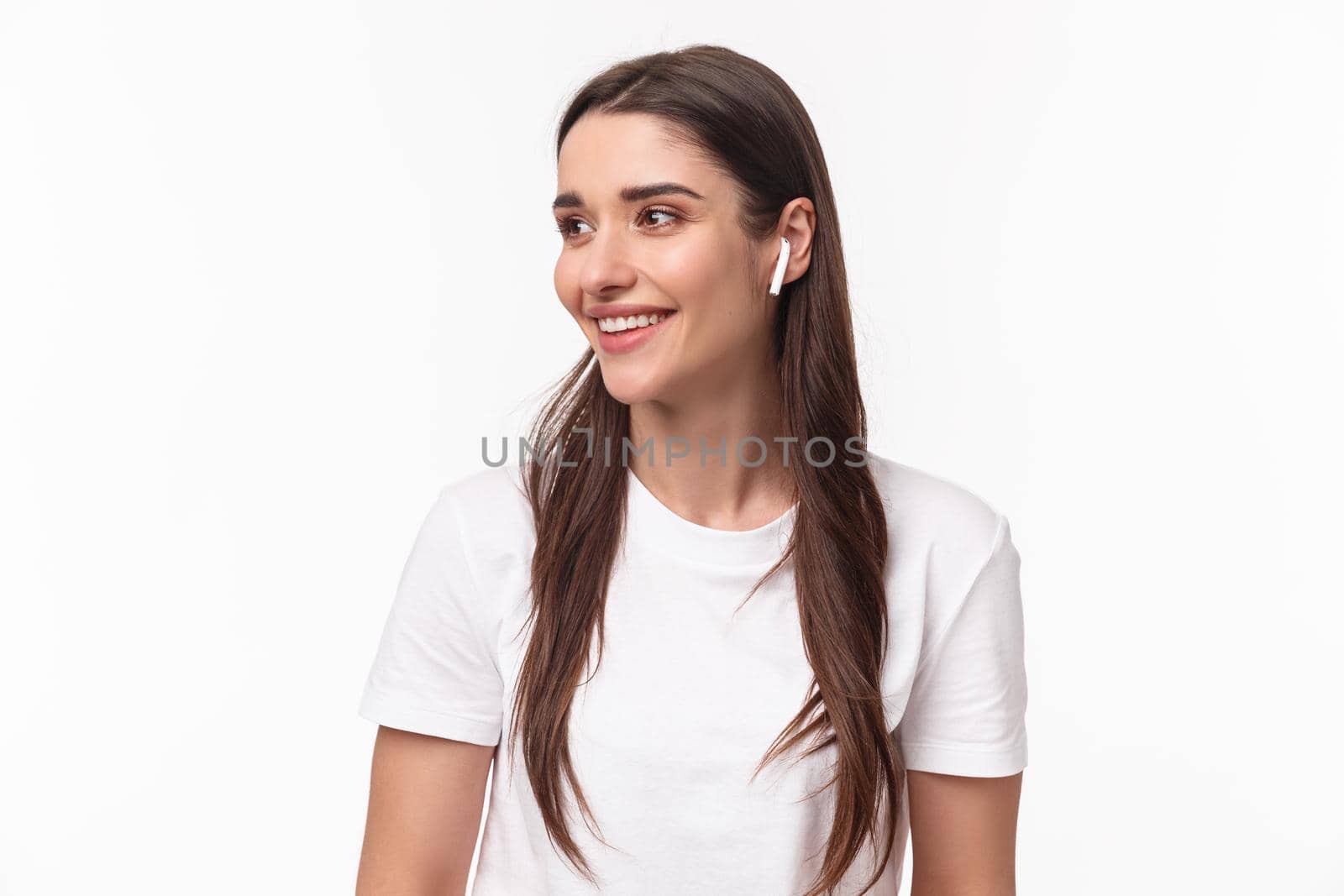 Close-up portrait of lovely, pretty young woman in t-shirt, listening music in wireless headphones, look away with pleased smile, enjoying favorite podcast or songs playlist, white background by Benzoix