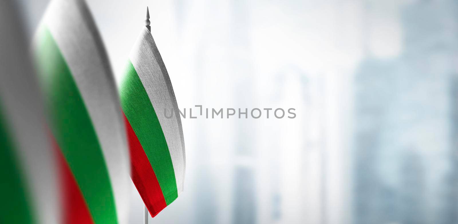 Small flags of Bulgaria on the background of an urban abstract blurred background.