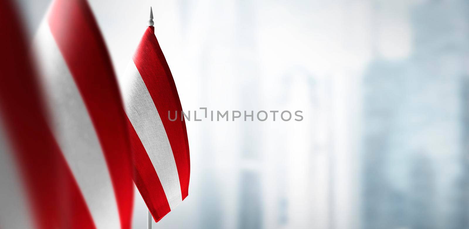 Small flags of Austria on the background of an urban abstract blurred background.