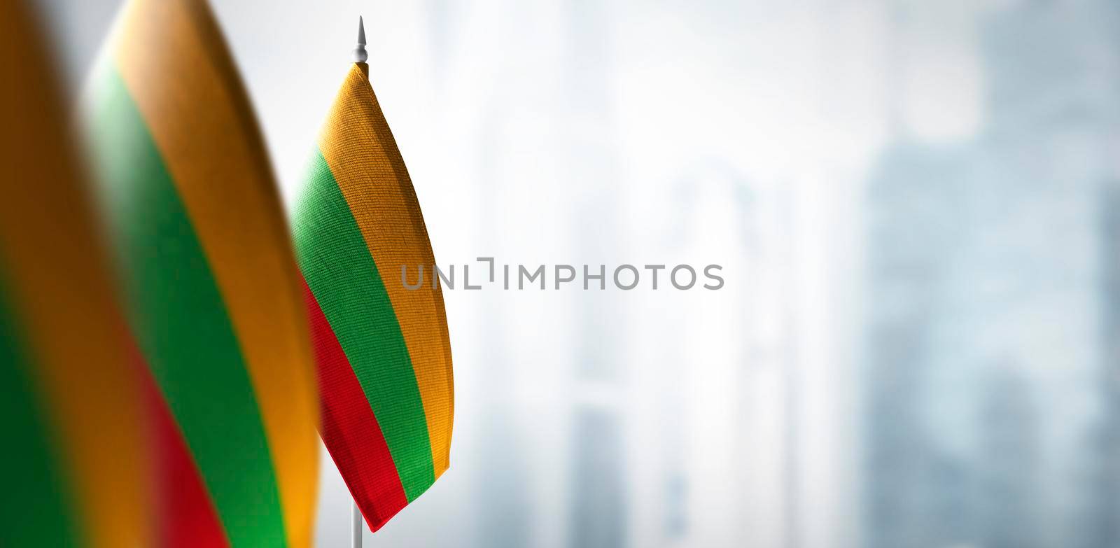Small flags of Lithuania on the background of an urban abstract blurred background.