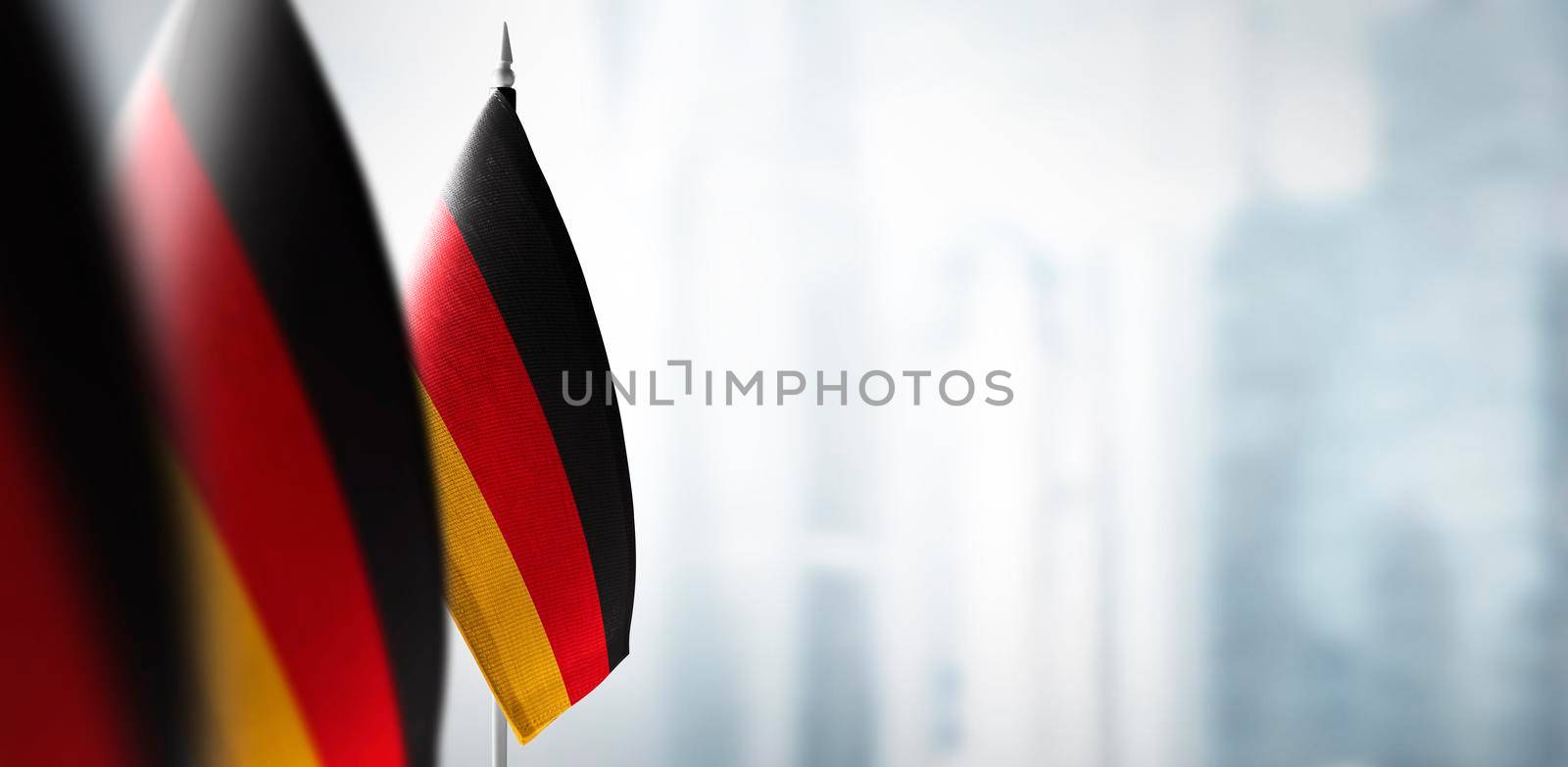 A small flag of Germany on the background of an urban abstract blurred background.