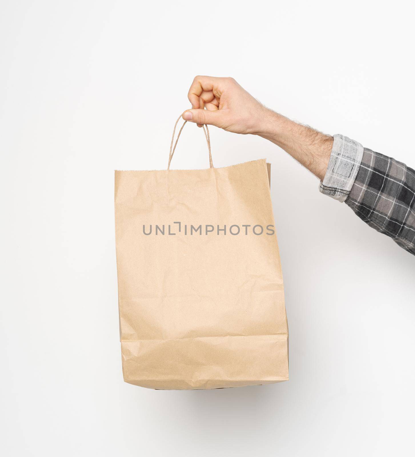 Male hand in plaid shirt twisted sleeve hand holding brown paper bag isolated on white background. Delivery concept. Paper bag for takeaway food. Square crop.