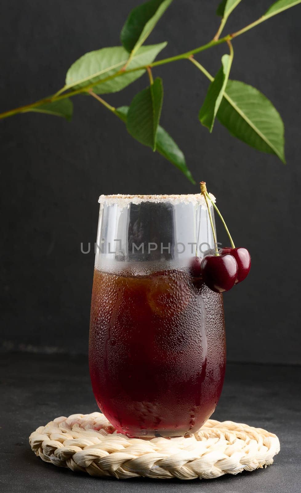 Cherry juice in a glass on a black background