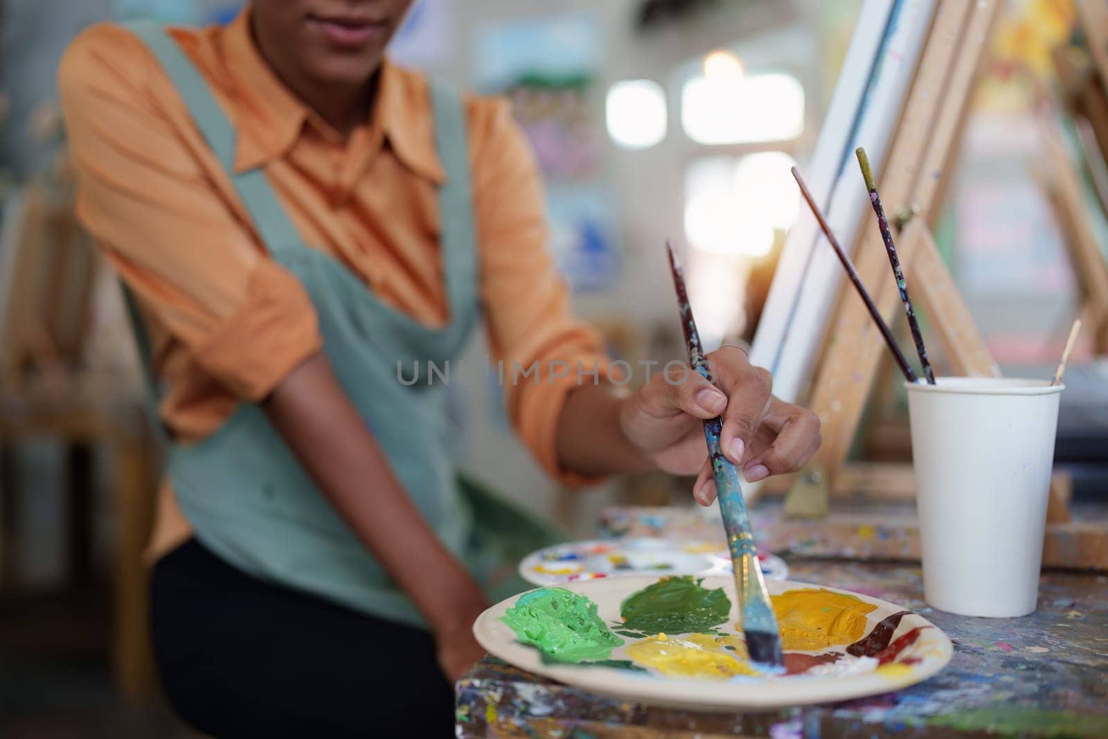 Beautiful american african artist woman painting in art studio at the university classroom by itchaznong