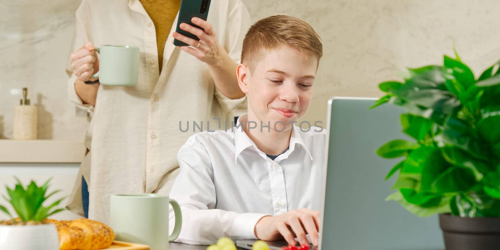 Happy mother and son have healthy breakfast in the kitchen at home. Happy mother and son in the kitchen. breakfast and digital devices Concept of happy family and healthy food.