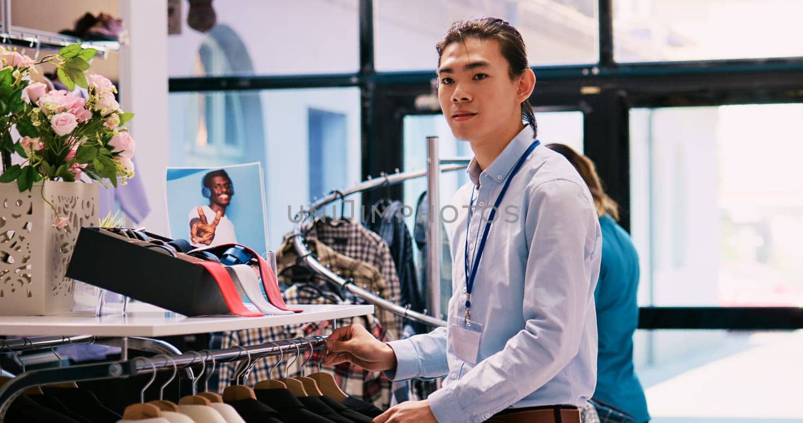 Worker arranging hangers with clothes by DCStudio