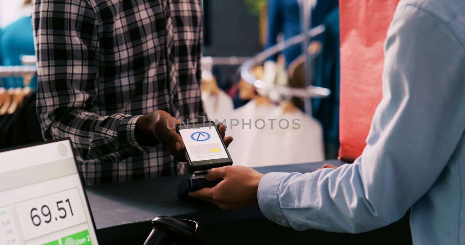 African american man paying for casual wear using mobile phone nfc on pos terminal, buying stylish clothes and accessories in clothing store. Customer shopping for trendy merchandise