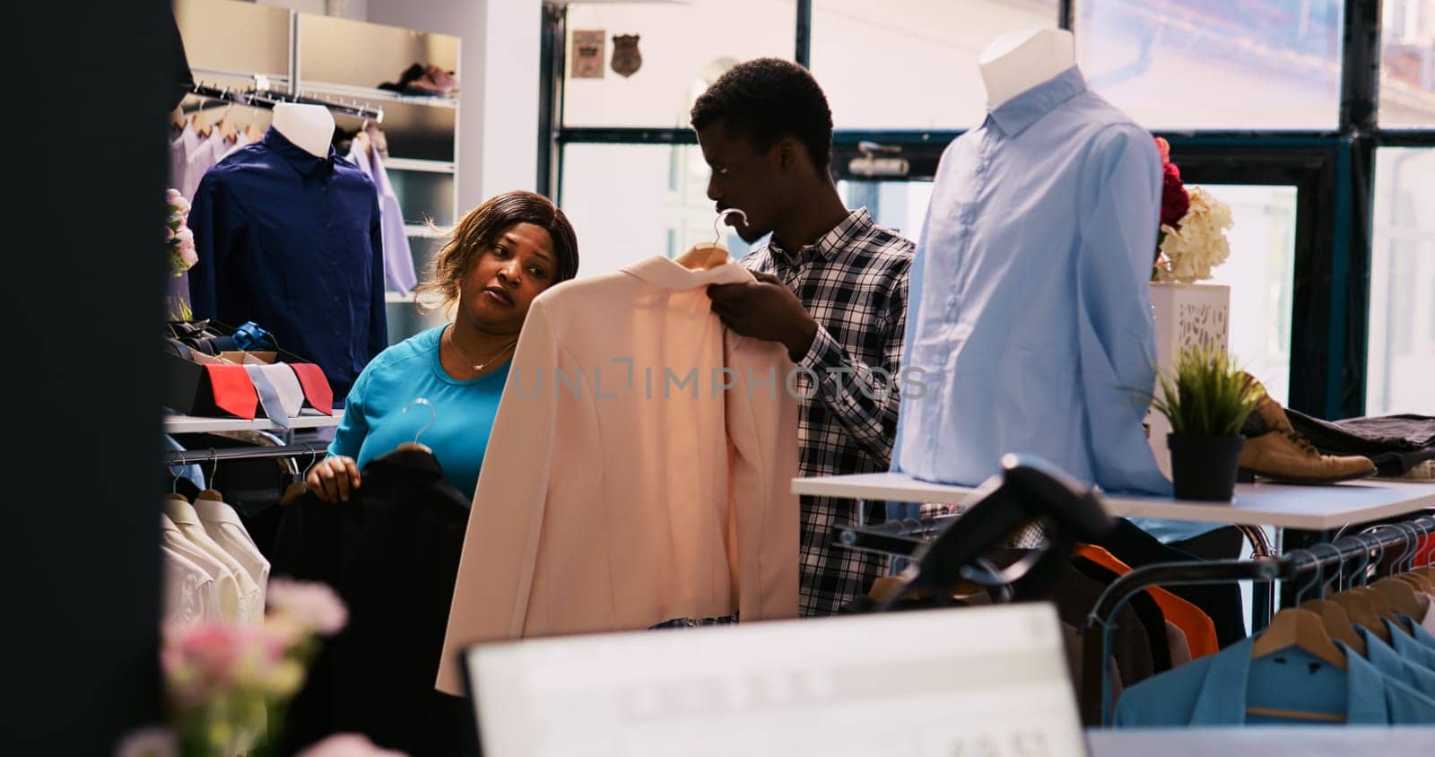African american couple looking at trendy merchandise, checking clothes fabric before buying it. shopaholic customers shopping for fashionable outfit and stylish accessories in modern boutique