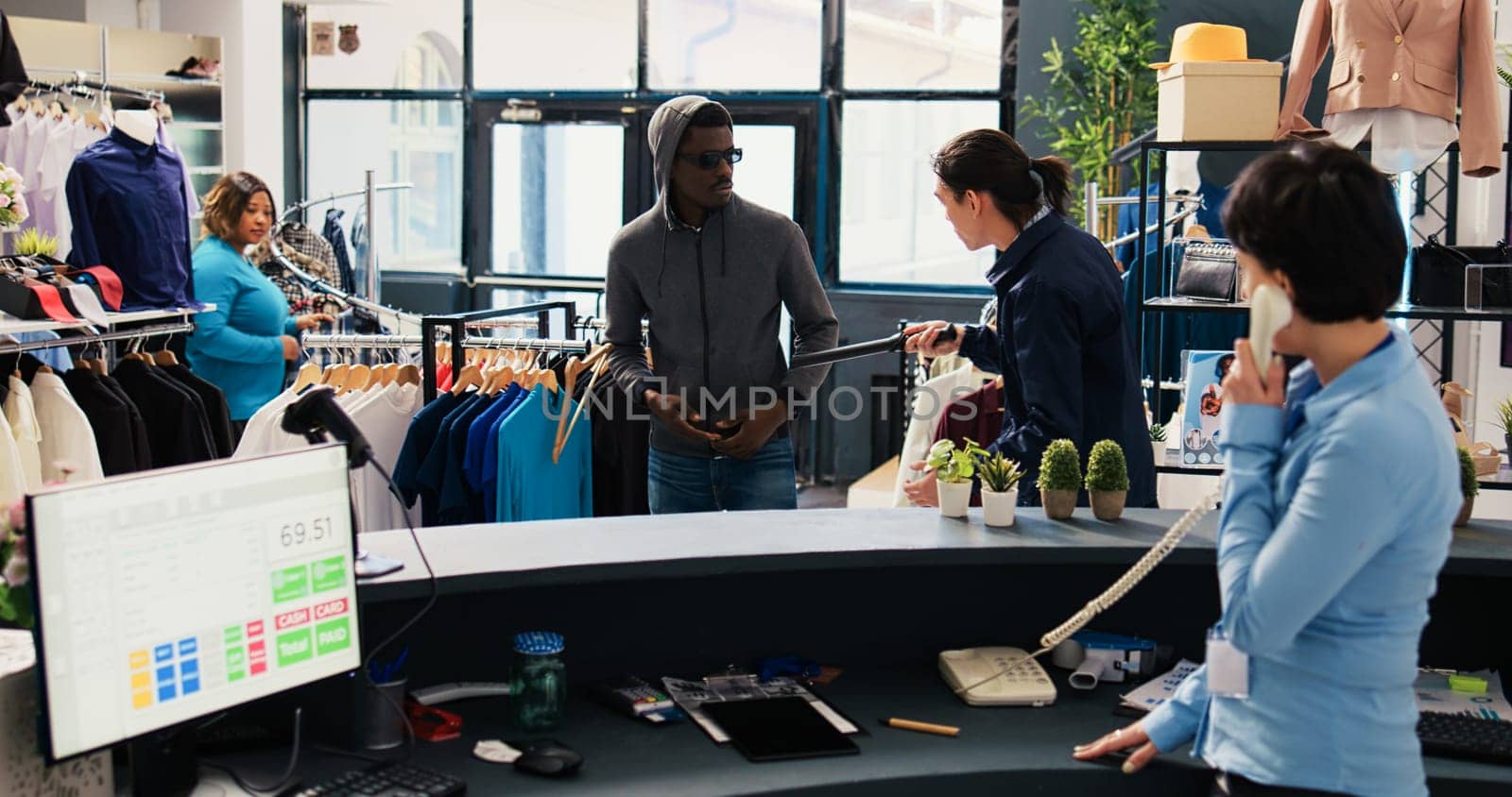 African american robber trying stole stylish shirt being caught by store security guard in shopping mall. Asian bodyguard asking thief to return fashionable merchandise or will call the police