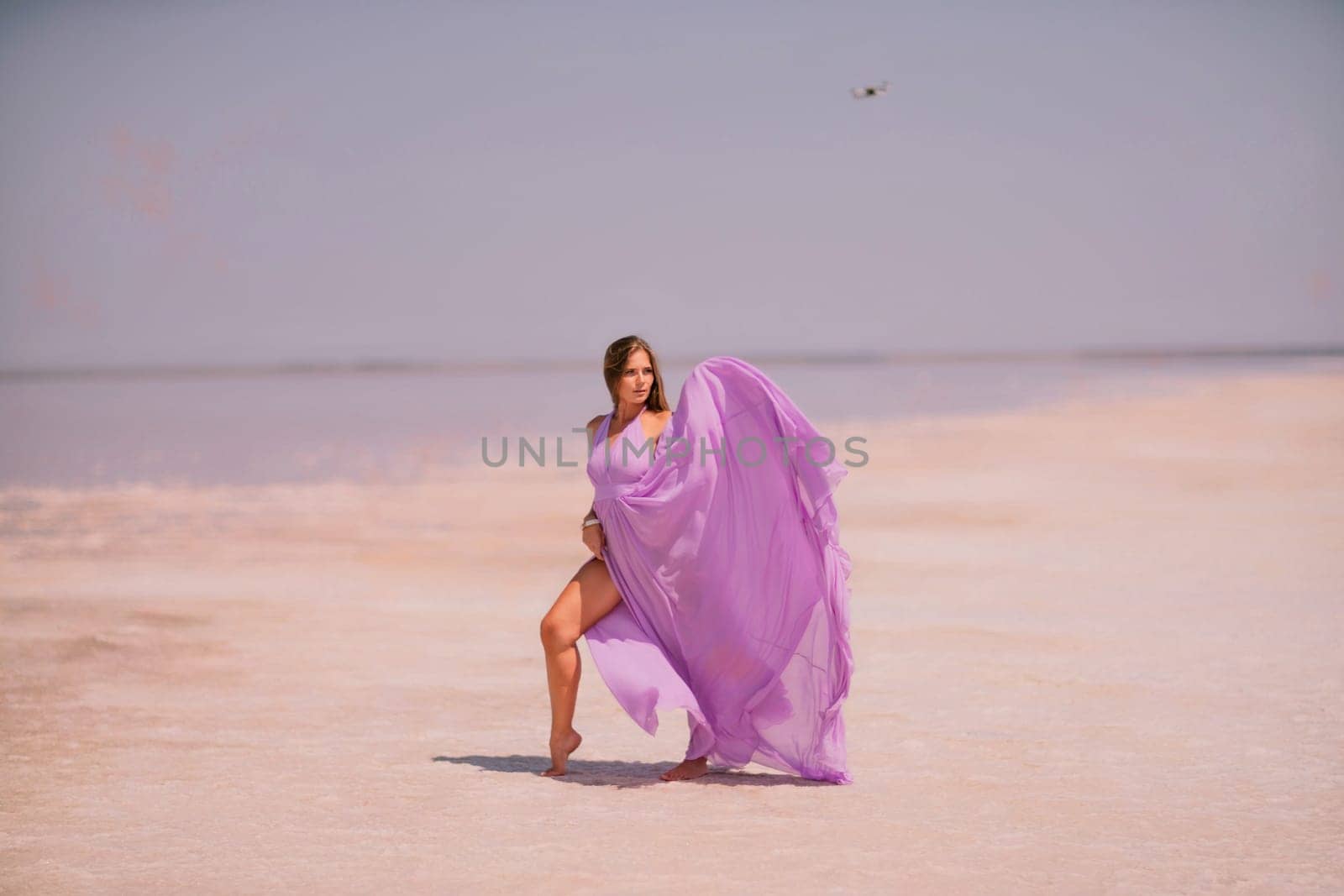 Woman pink salt lake. Against the backdrop of a pink salt lake, a woman in a long pink dress takes a leisurely stroll along the white, salty shore, capturing a wanderlust moment. by Matiunina