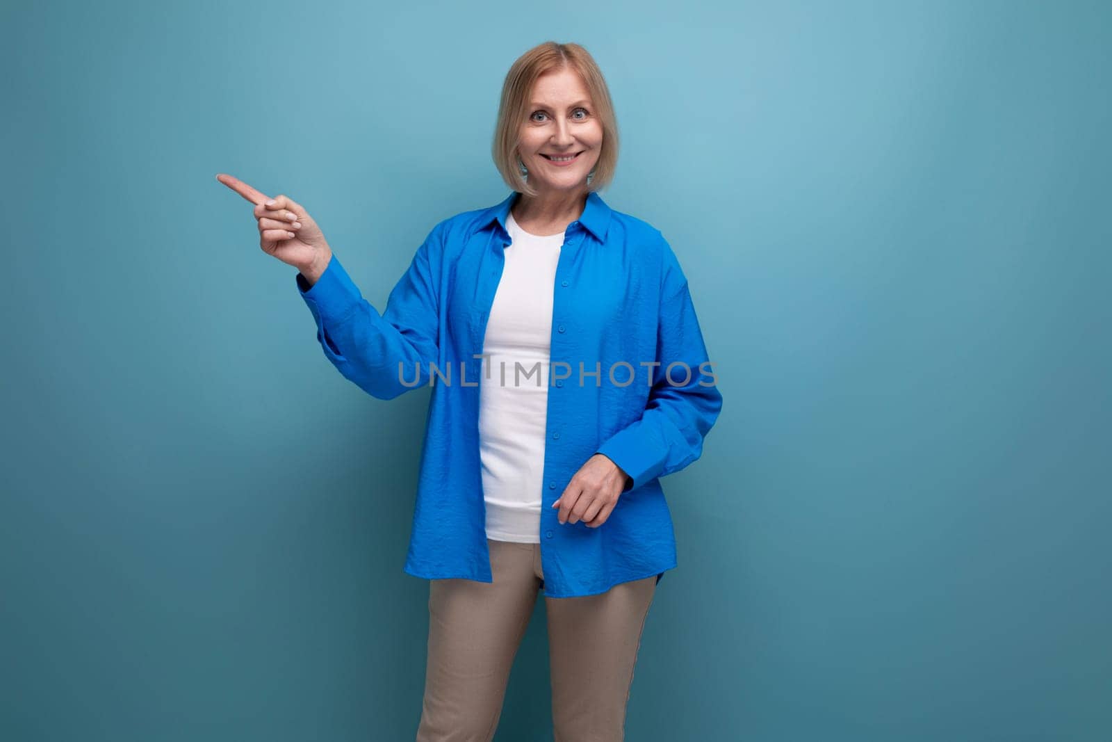 close-up of a mature woman in a blue shirt with an idea on a blue background with copy space.