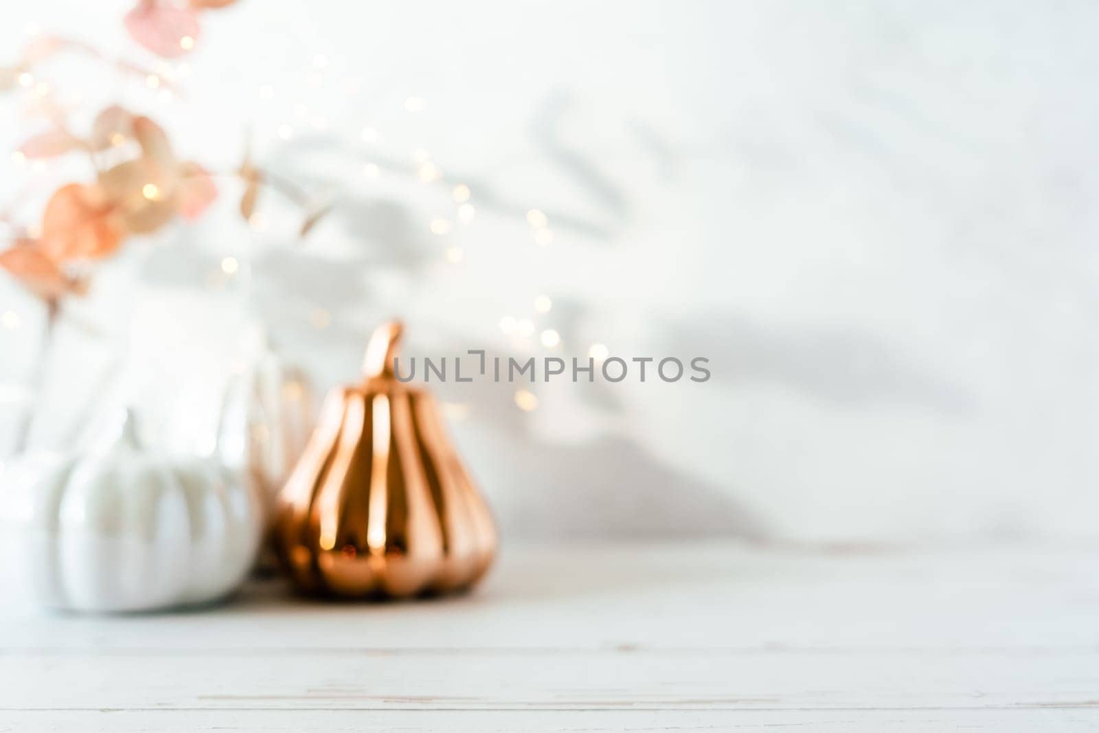 Blurred Details of Still life, pumpkins, candle, brunch with leaves on white table background, home decor in a cozy house. Autumn weekend concept. Fallen leaves and home decoration