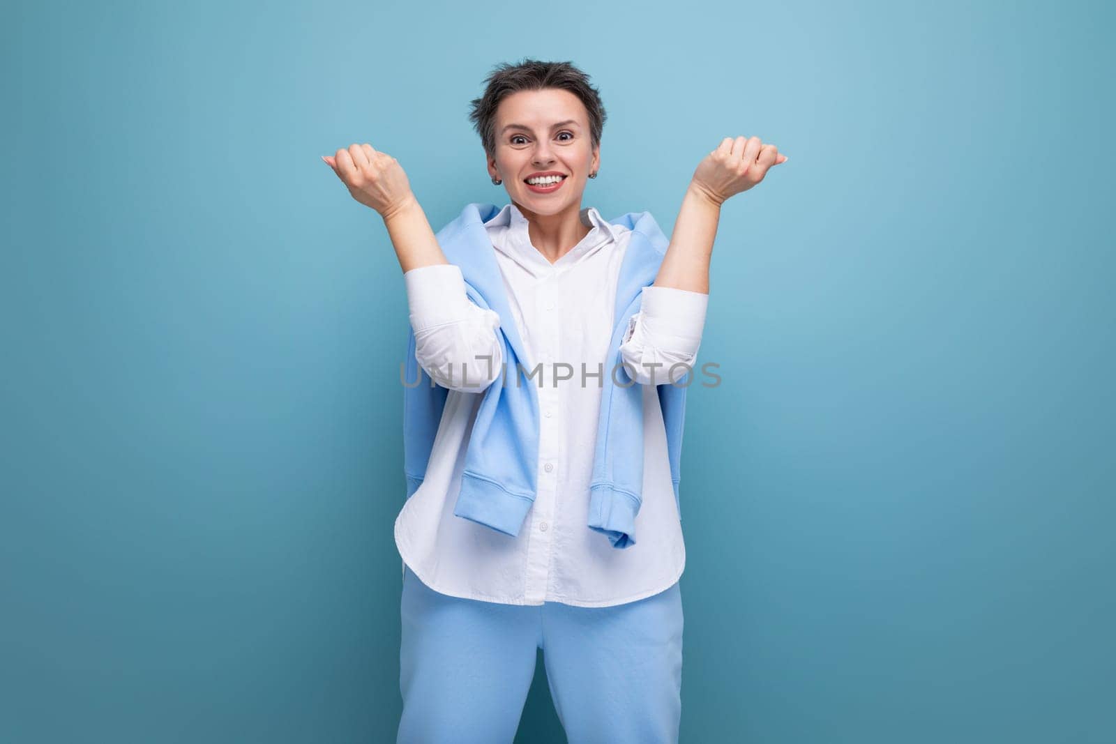 smiling young woman with short haircut in white shirt and blue pants.