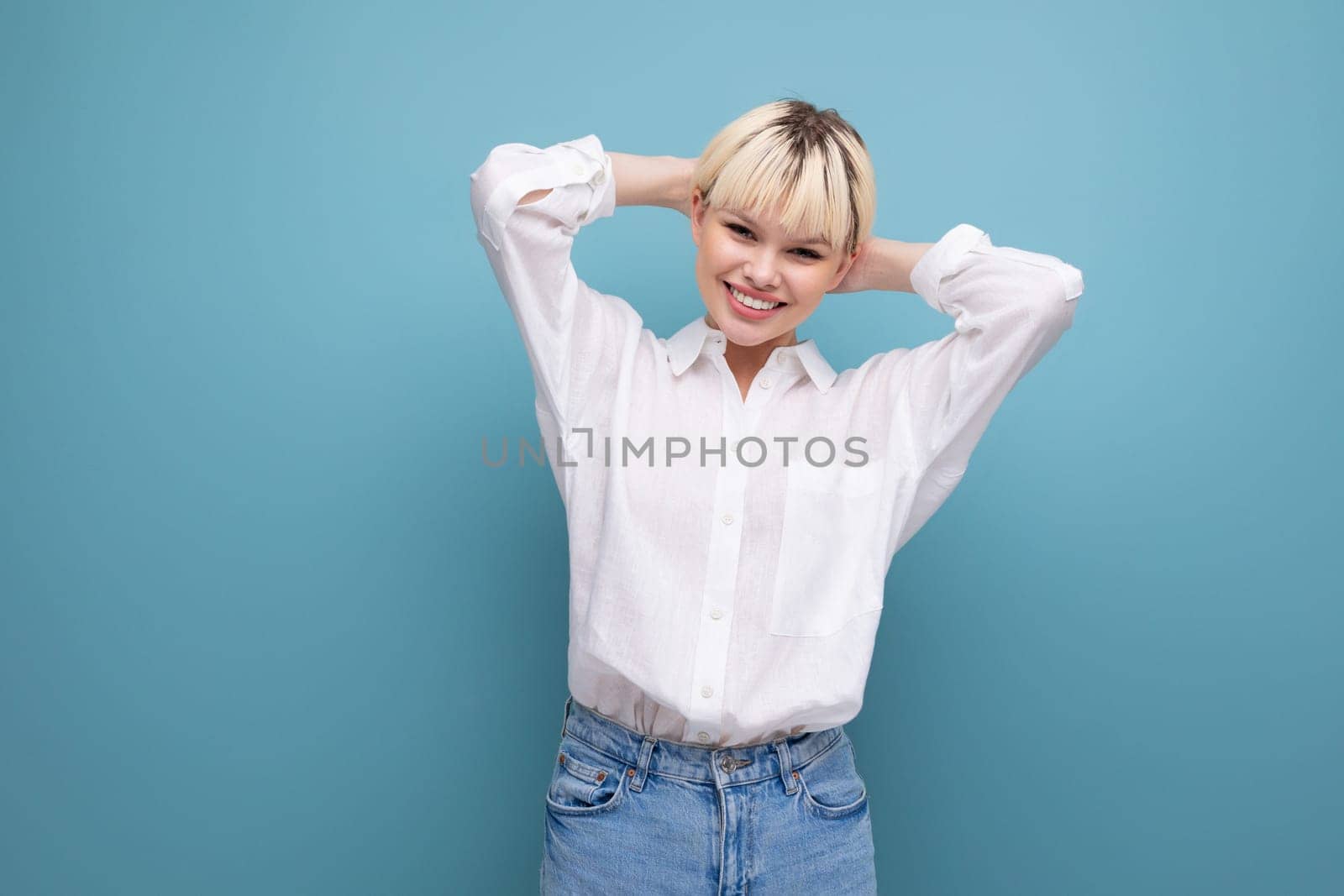 young cute blond fashionable woman with short haircut is dressed in a white shirt and jeans. casual wear concept.