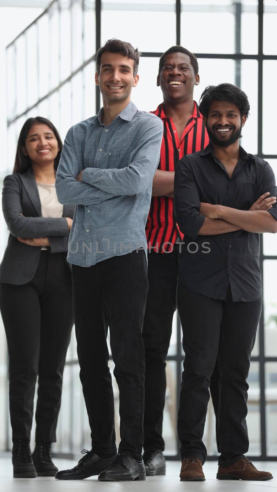 a professional group of diverse business people in casual wear stand in the office with their arms crossed