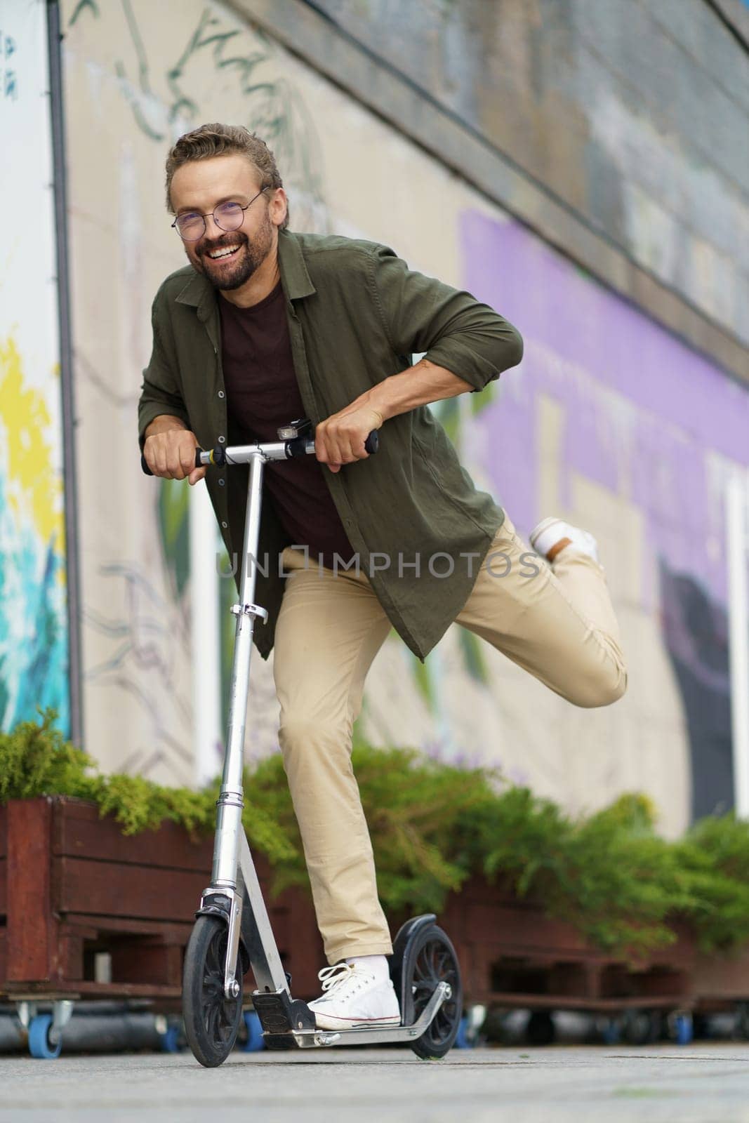 Fun and happy life as a smiling man rides a scooter on the street. With a beaming smile and an expression of pure joy, he embraces the sense of freedom and adventure that comes with scooter riding. High quality photo