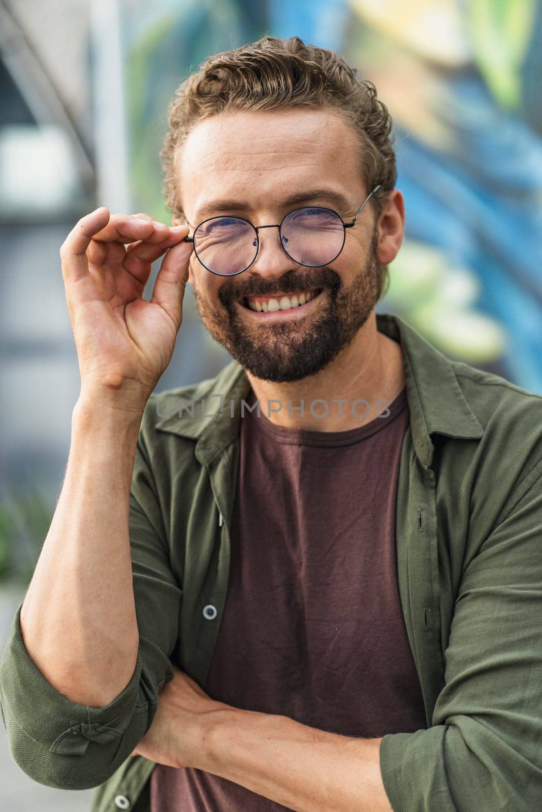 Happy man with warm smile, holding glasses. Joyful expression radiates positivity and contentment, showcasing sense of inner satisfaction. With confident and friendly demeanor, exudes approachability and charm. . High quality photo