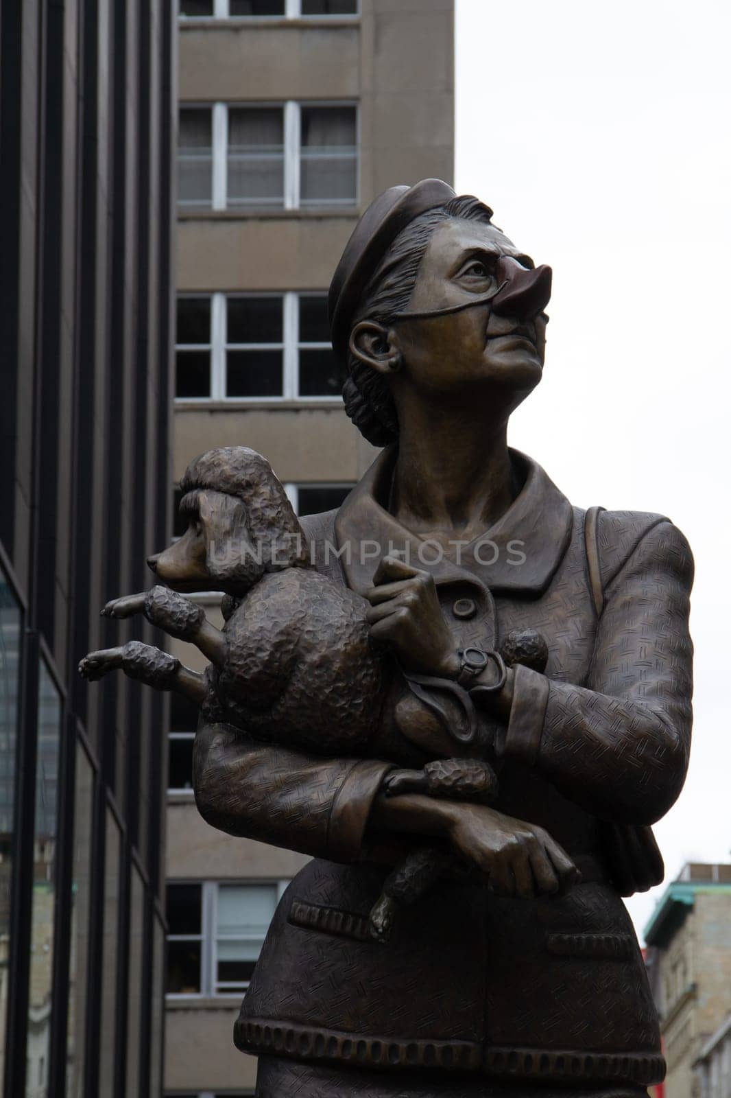 Bronze sculpture of a Frenchwoman holding a French Poodle while staring with discontent by Granchinho