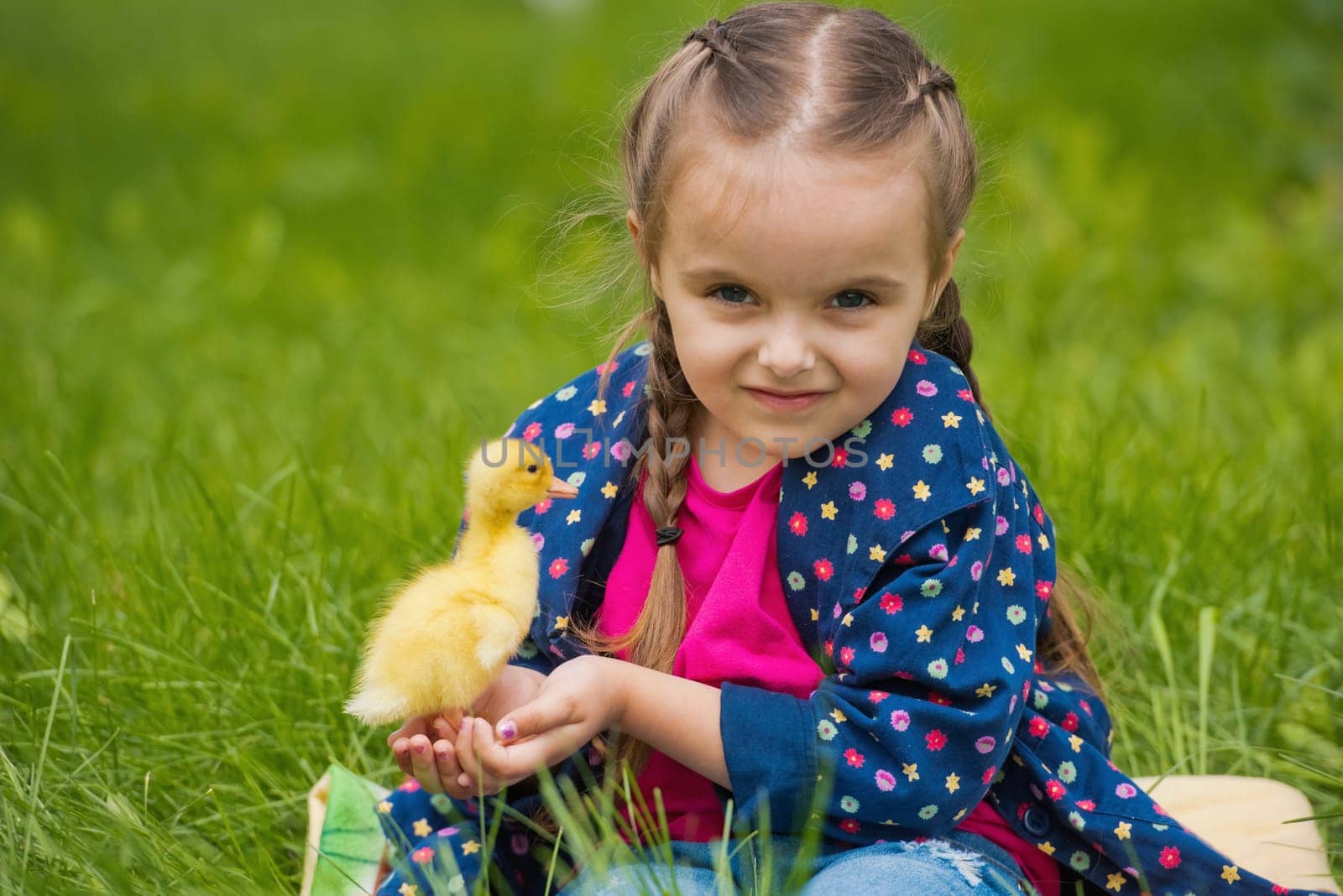 Cute happy little girl with of small duckling in the garden. Little girl holding a duckling in her hands.