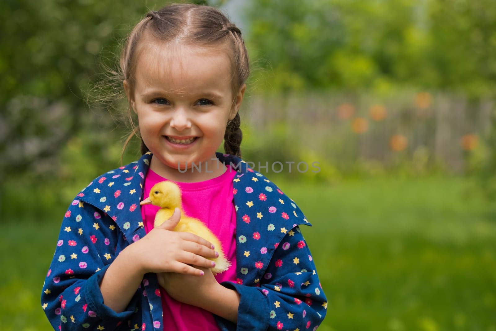 Cute happy little girl with of small duckling in the garden. Little girl holding a duckling in her hands.