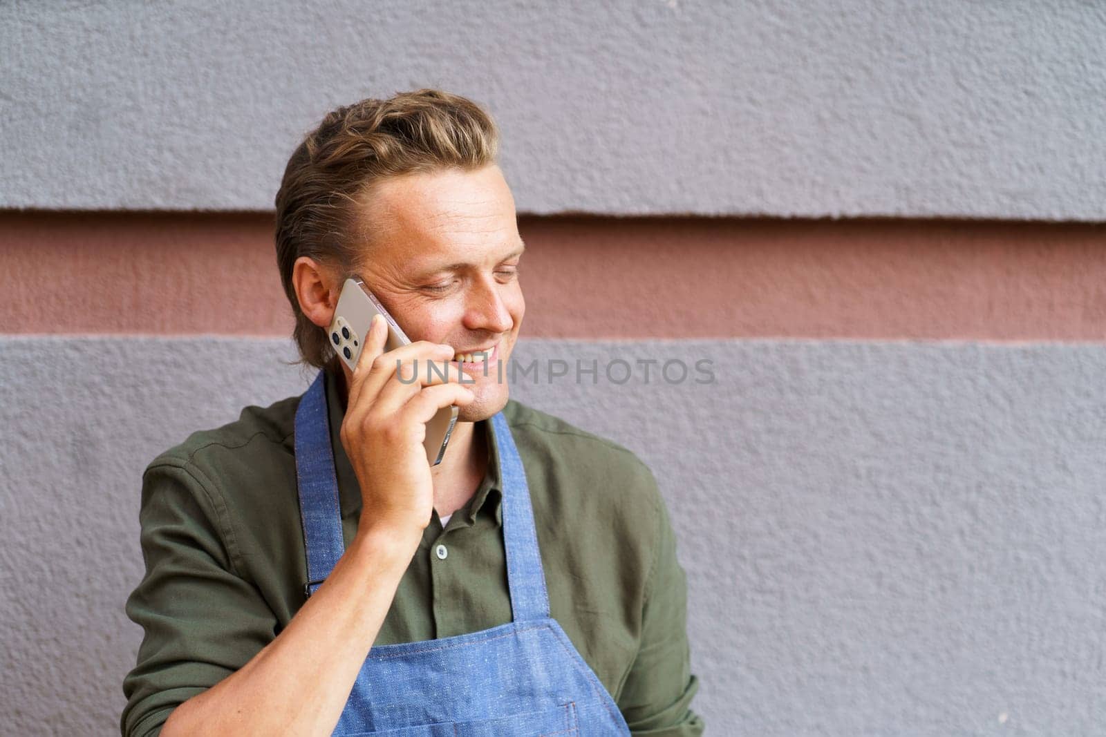 Restaurant worker receive call from client on mobile phone. With focus on communication and customer service, worker exemplifies dedication and multitasking abilities required in restaurant industry. . High quality photo