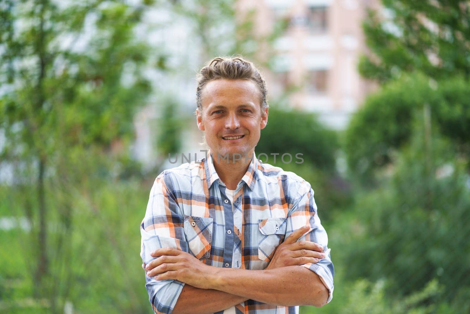 Man on the street with crossed hands, exuding a sense of confidence and composure. With a relaxed posture and a calm demeanor, he navigates the urban environment with ease. High quality photo
